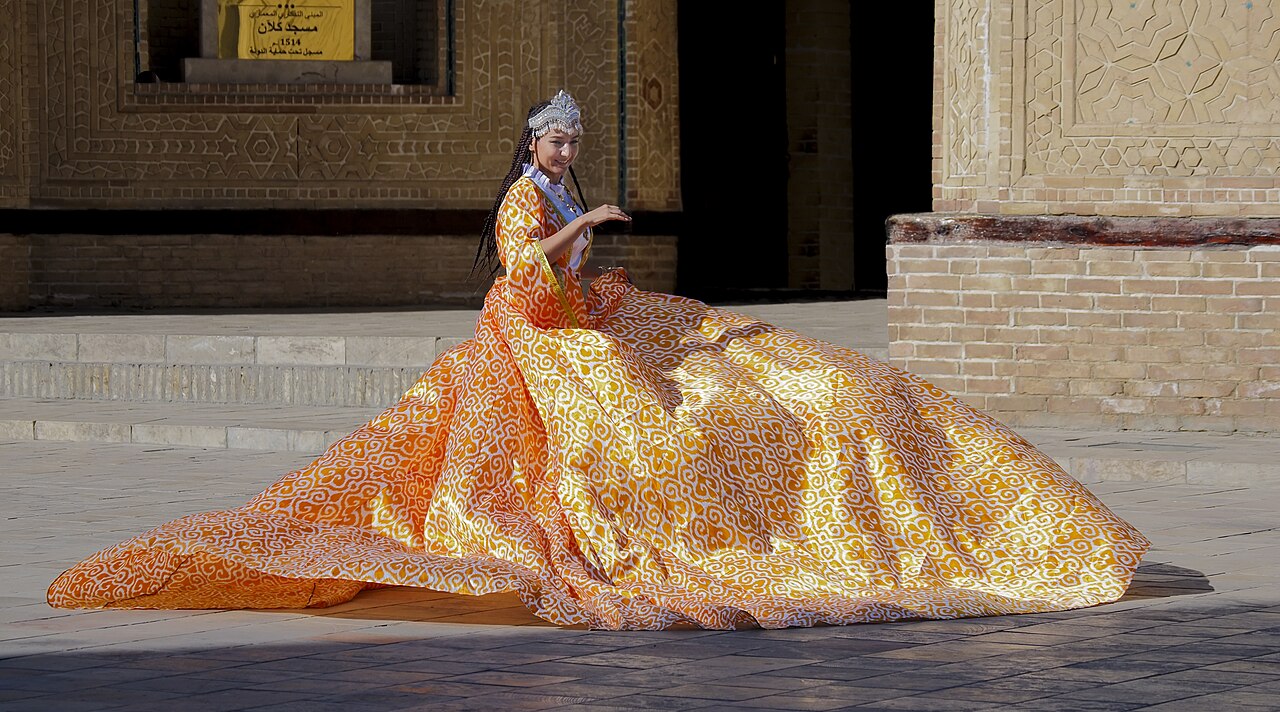 Woman in traditional Uzbek long adras dress (Po-i-Kalyan complex, 2025 Buhara)